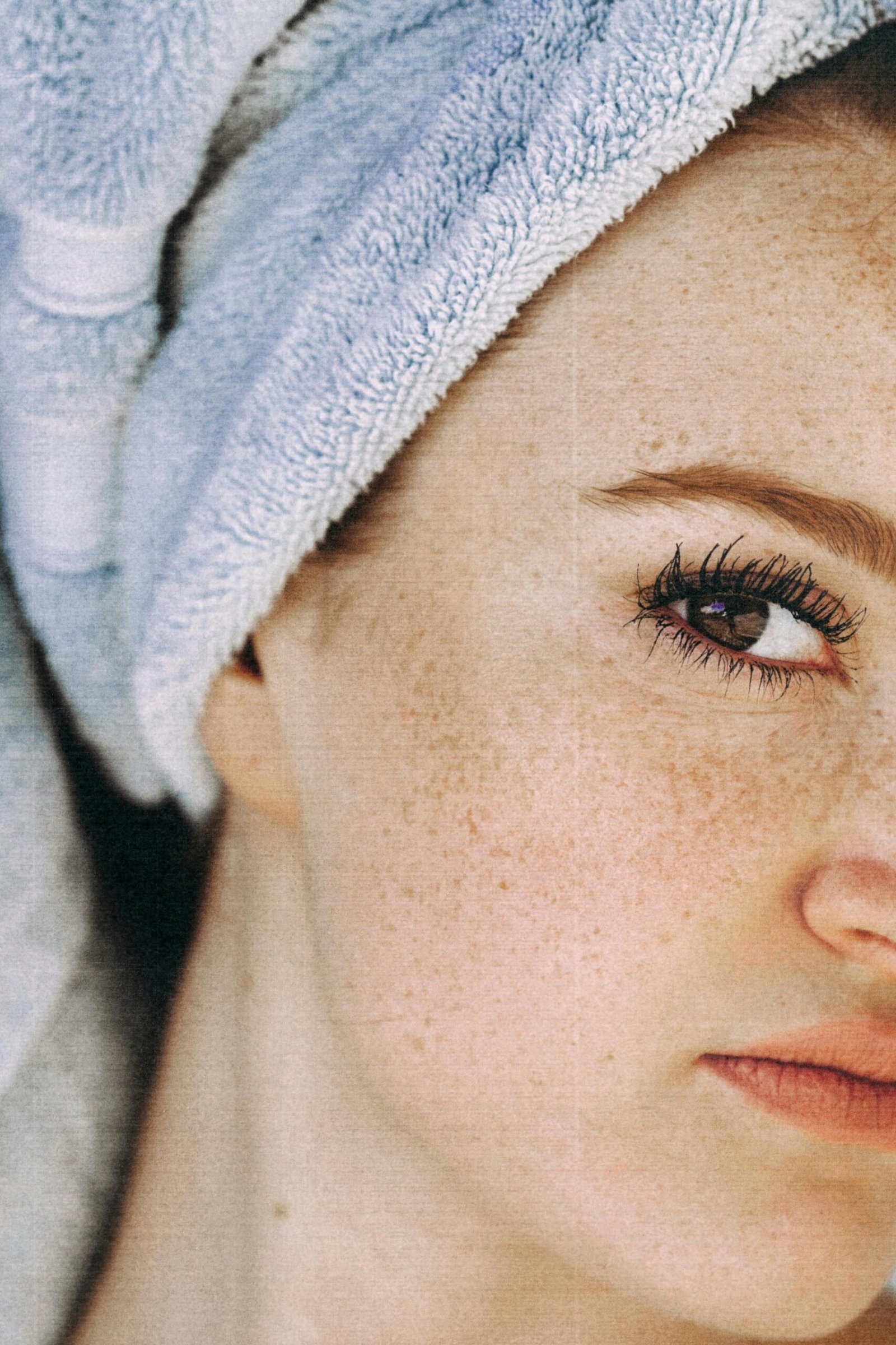 A close-up of a person with a towel on their head, focusing on one eye and part of the face.